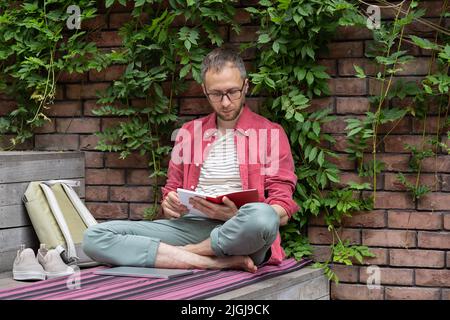 Caucasian guy sitting at stairs outdoor holding science history book or training material book Stock Photo