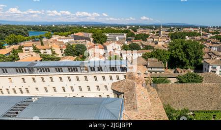 Modern apartment buildings are being built on the site of Avignon's former prison, seen here across the tiled rooftops of the old town toward the Rocher des Doms, France. Stock Photo
