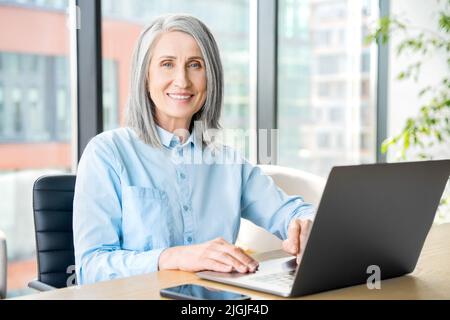 Senior businesswoman sitting at working place and looking at camera Stock Photo