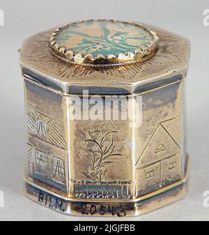 Dosa Odor box/mushroom box of gilded silver, made by Johan Wilhelm Hultgren, Karlskrona.åttkantig shape, lid with hinges. The lid with round flower painting under glass. The sides with engraved houses and trees. Stamped below the bottom; Manufacturer stamp JWH, control stamp, city weapon Karlskrona, year stamp G5. Engraved below the bottom; Hod.width over flats 31 cm. Testamentary Gift. Negative number: 95:91, 4. Literature: Bengtsson, Bengt Old Silver from Culture's collections. Västerås 1979. Stock Photo