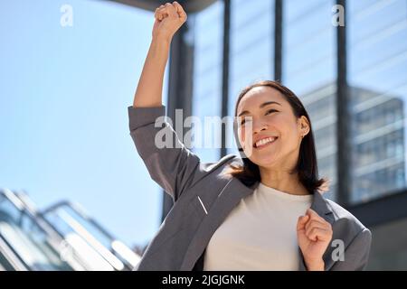 Young excited happy Asian business woman celebrating success in city. Stock Photo