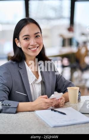 Young happy Asian business woman wearing suit using smartphone. Portrait Stock Photo