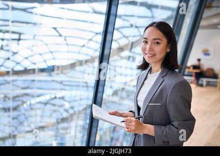 Smiling young Asian business woman manager standing in office. Stock Photo
