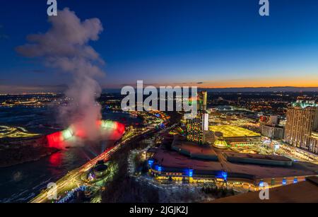 Aerial view of Horseshoe Falls winter illumination in twilight time. Niagara Falls City downtown horizon. Stunning landscape dusk to night. Stock Photo