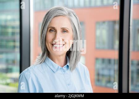 Portrait of smiling confident 60-s gray-haired mature woman. Stock Photo