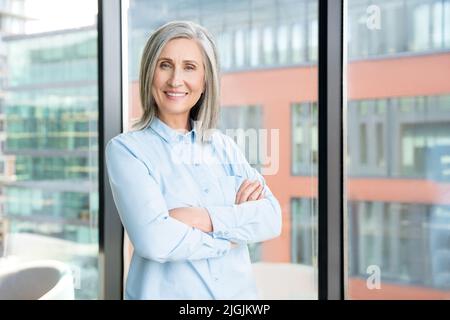 Portrait of smiling confident 60-s gray-haired mature woman. Stock Photo