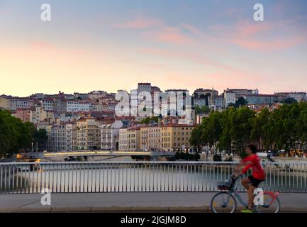 Cyclist and View over Saone River towards Hillside Neighborhood or Croix-Rousse, Lyon, France Stock Photo