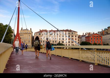 People crossing Passerelle du Palais de Justice Bridge over Saone River looking towards central Lyon, France Stock Photo