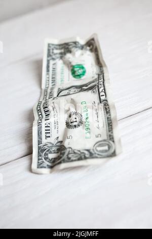 Crumpled one dollar on white wooden background Stock Photo