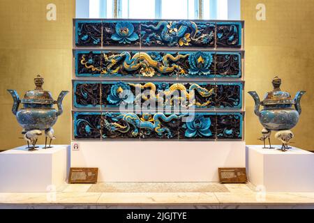 London, UK - 18th April 2022: Ming Dynasty glazed ceramic dragon tiles, dating from 15th to 16th century China, and two Cloisonne incense burners, Bri Stock Photo