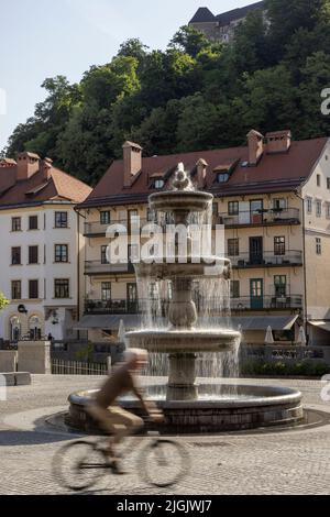 Bicyclist in front of Novi Trg fountain on the Ljubljanica River Embankment, Ljubljana, Slovenia Stock Photo