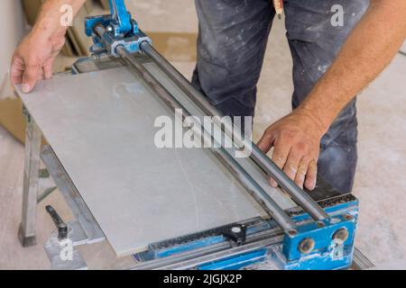 Using manual tools equipment, a construction worker cuts the ceramic tile using manual tools for laying ceramic tiles Stock Photo