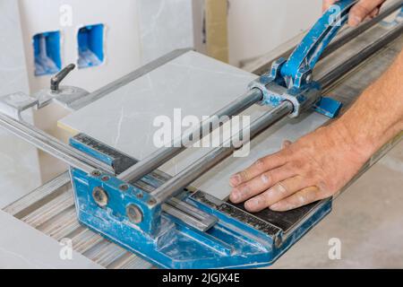 Construction worker cuts ceramic tile floors using manual tools equipment for laying ceramic tiles on a floor Stock Photo