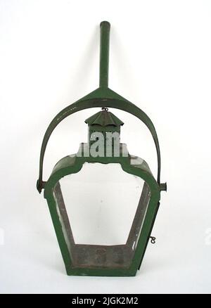 Stånglykta Bar lantern, service lantern of tin green painted. Suspended on a fork position and thus moving. One of the glasses gone. On one short side only half the glass left. Inside the lantern candle holder for three candles. Stock Photo