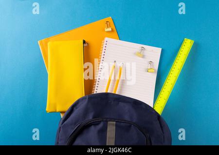 Image of school supplies, notebook, backpack, ruler, paper clips on blue background Stock Photo