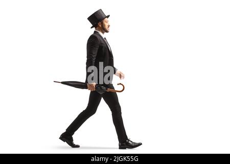 Full length profile shot of a man in a suit and top hat walking and carrying an umbrella isolated on white background Stock Photo