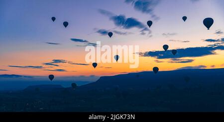 hot air balloons fly at sunrise over the city of Goreme in Turkey. Stock Photo