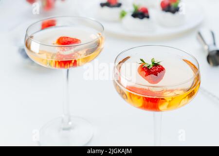 Cocktail drinks with fresh strawberry and meringue Pavlova cakes with fresh strawberries and blueberries on the white plate on the background. Dessert Stock Photo