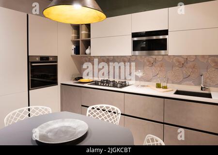 Interior of kitchen with modern furniture and built in appliances illuminated with bright lamp at home Stock Photo