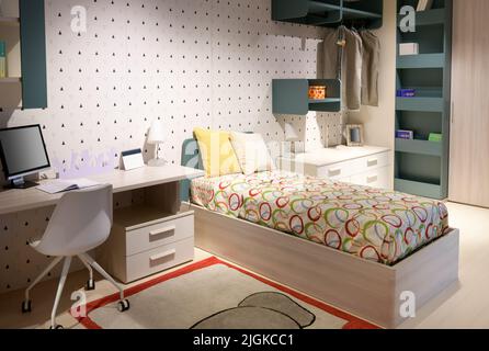 Desk with computer and soft bed located in contemporary teenager bedroom at home Stock Photo