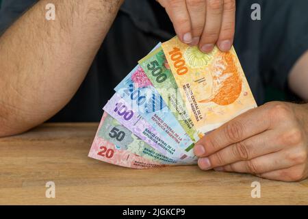 Argentine money, Business success, lottery win Creative financial concept, Man in shirt holds spread out money in his hands, Bundle of new banknotes a Stock Photo