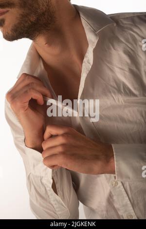 Handsome man undoing his shirt in a photoshoot in the studio Stock ...