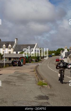 Cyclist carrying a rucksack and a bucket on his back, Pier Road, Lochboisdale, South Uist, Outer Hebrides, Scotland Stock Photo