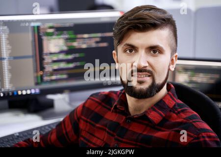 Computer programmer developer working in IT office, sitting at desk and coding, working on a project in software development company or startup. Stock Photo