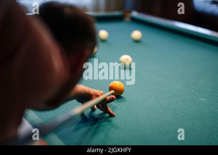 Young man playing billiard indoors. Spending free time on gambling. Stock Photo