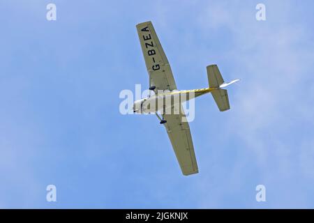 Cessna A152 Aerobat G-BZEA flying overhead against a blue sky. Stock Photo