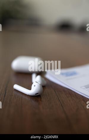 white wireless headphones with a case are on the table. Stock Photo