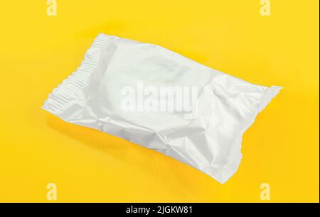 Silver foil dessert packaging isolated on yellow background Stock Photo