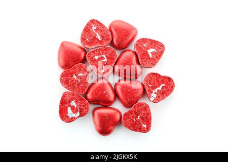 Group of heart shaped chocolate candies wrapped in red foil isolated on white background Stock Photo