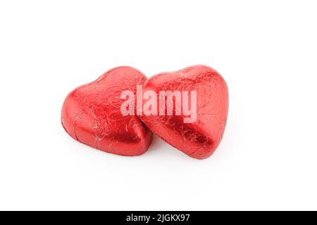 Pair of heart shaped chocolate candies wrapped in red foil isolated on white background Stock Photo