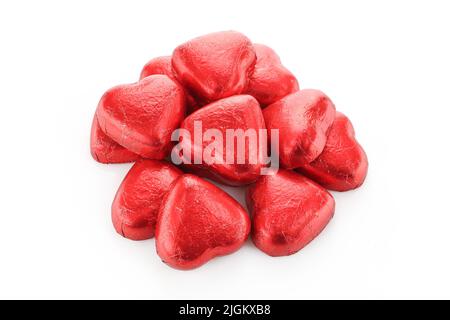 Group of heart shaped chocolate candies wrapped in red foil isolated on white background Stock Photo