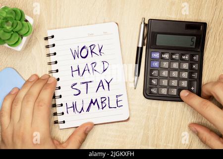 WORK HARD STAY HUMBLE word inscription on white card paper sheet in hands of a man. Black letters on white paper. Business concept. Stock Photo