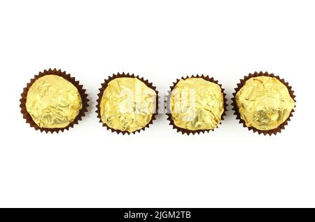 Four chocolate truffle balls wrapped in golden color foil isolated on white background Stock Photo