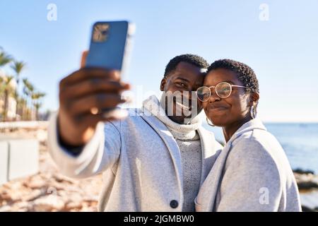 Man and woman couple standing together make selfie by the smartphone at seaside Stock Photo