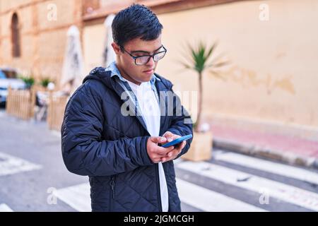 Down syndrome man using smartphone at street Stock Photo