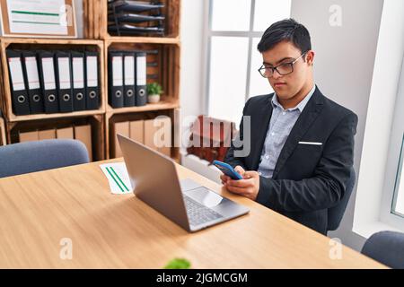 Down syndrome man business worker using smartphone at office Stock Photo