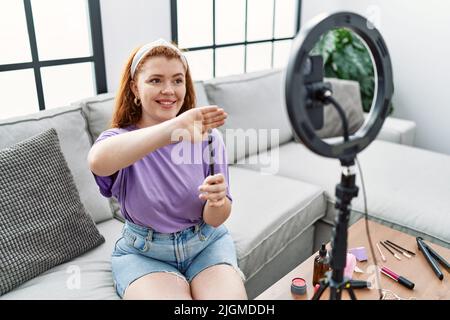 Young redhead woman making makeup tutorial using smartphone at home Stock Photo