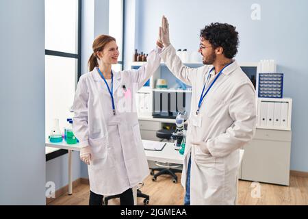 Man and woman scientist partners high five with hands raised up at laboratory Stock Photo