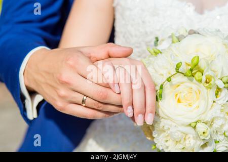 The couple cuddling and holding bridal bouquet. Hands close-up. Stock Photo