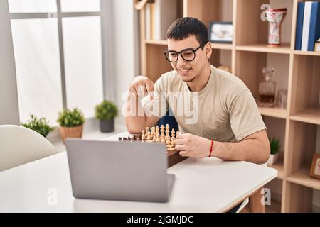 Young arab man playing chess online smiling happy pointing with hand and finger Stock Photo