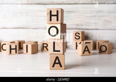 Word HOLA (HELLO) made of wooden cubes on light table Stock Photo
