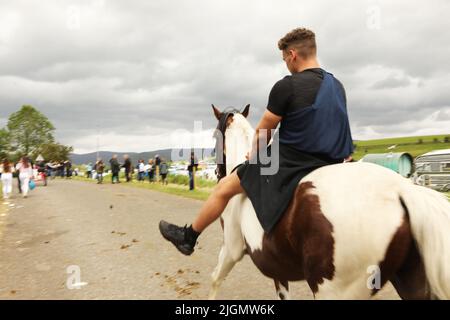 A young man trotting along the road on a coloured gypsy cob horse. Appleby Horse Fair, Appleby in Westmorland, Cumbria, England, United Kingdom Stock Photo