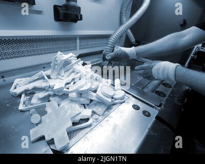 Man cleans details printed on industrial 3D printer from white plastic powder. Automated additive technologies. Person cleans vacuum cleaner plastic powder from models printed on 3D printer. Top view Stock Photo