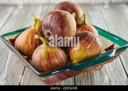 Fresh figs In green plate on wooden background Stock Photo