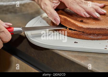Chef cuts the chocolate cake in two to make pear and walnut pie Stock Photo