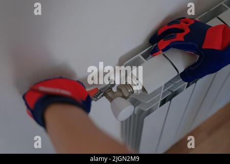 Male plumber installing heating radiator using pipe wrench Stock Photo